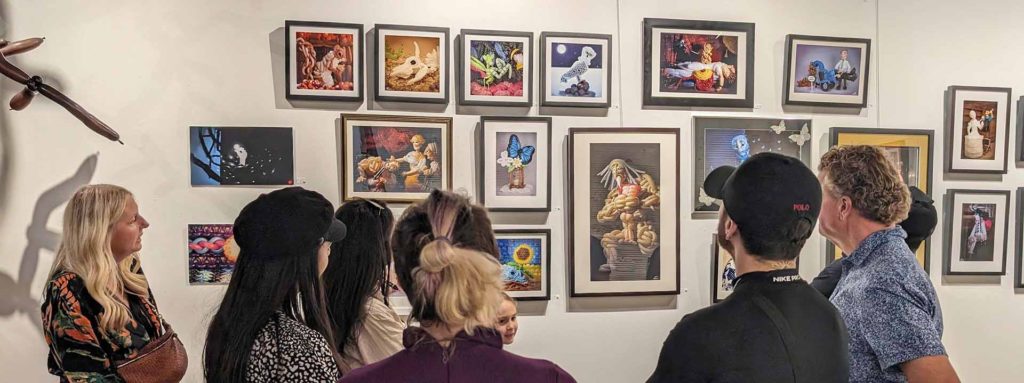 DJ Morrow with visitors viewing prints on display at messengers balloon art exhibition