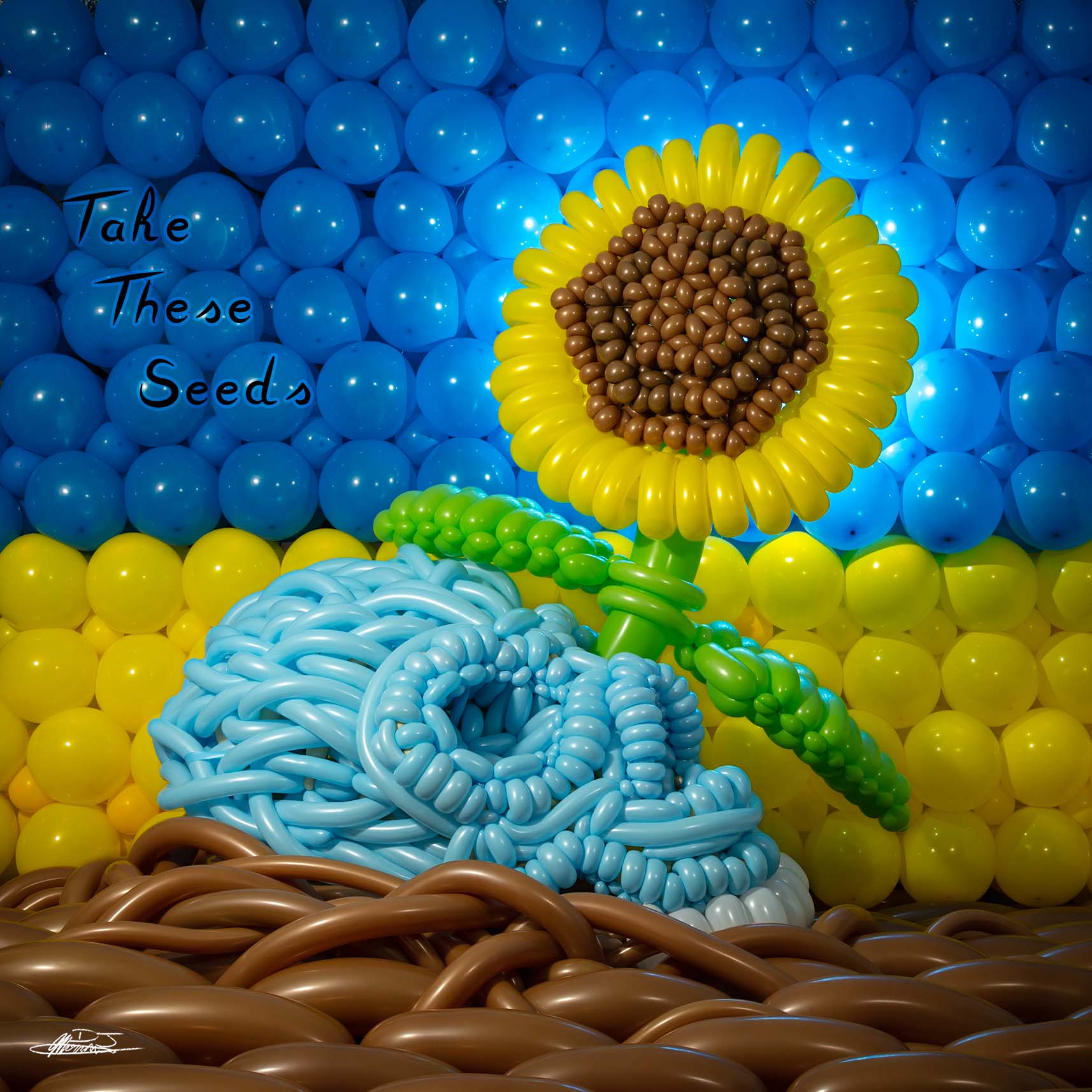 Take These Seeds balloon sculpture of a skull on the ground with a sunflower growing out of eye socket in front of ukranian flag