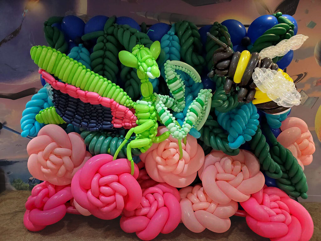 to fight balloon sculpture relief of praying mantis fighting bumblebee on rose and leaf backdrop