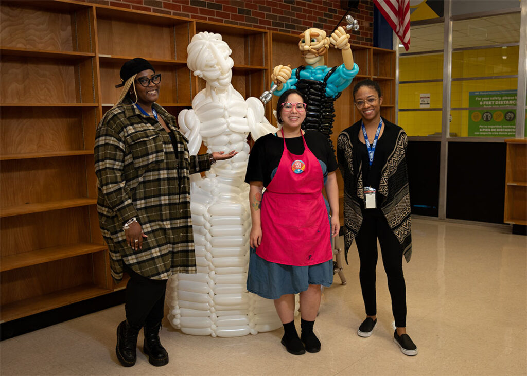 school staff standing with the sculptor balloon sculpture of artisan carving a marble statue